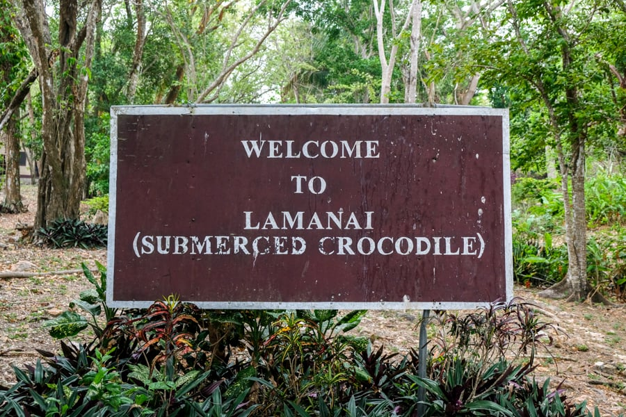 Welcome sign at the entrance of the Lamanai archaeological site in Belize, marking the beginning of the path to the ancient Mayan ruins, surrounded by lush greenery.